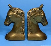 Front view of the pair of brass horse head bookends showing detailed sculpted mane and facial features.