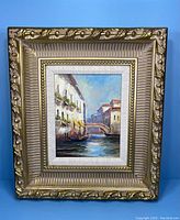 Front view of the framed oil painting showing the canal scene with gondolas and the ornate gold frame.