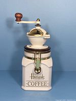 Front view of the ceramic coffee mill jar showing the Harrods label and hand crank handle.