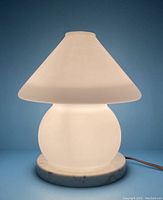 Front lit view of vintage mushroom lamp glowing, showing diffused light and marble base.