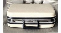Front view of closed vintage Jetliner hard shell suitcase showing textured beige shell, chrome trim, black handle, and metal latch