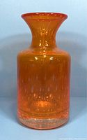Front view of the translucent orange glass vase with bubble inclusions and thick clear base, showing shape and size.