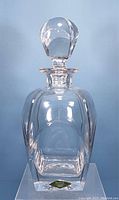 Clear crystal decanter with faceted rounded square body, heavy base, and teardrop stopper. Green Shannon label on base visible.