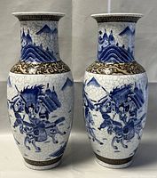 Pair of 15-inch tall ceramic vases with blue and white hand-painted warrior scenes and brown decorative bands at neck and base, shown front view.