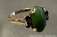 Front-side angle view showing oval jade center and garnet accents