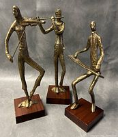 Set of three forged brass expressionist musicians on wooden bases, violin, flute, and keyboard players shown