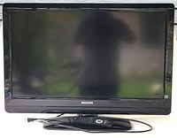 Front view of Philips television including screen and remote control placed on stand.