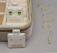 Earrings on display card marked 10 KT GOLD alongside necklace laid out on grey background