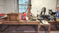 Overview of the workbench with band saw, grinders, and other tools against pegboard wall near window.