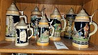 Rear side view of steins emphasizing pewter lids and handles