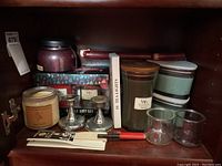 Full view of shelf with assorted candles, silver taper holders, candle gift set, and glass votive holders.