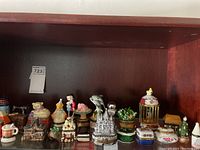 Wide view of all the assorted hinged trinket boxes in a wooden cabinet shelf