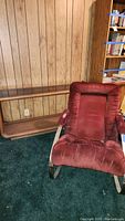 Wooden sofa table and velvet rocking chair side by side against wood-paneled wall