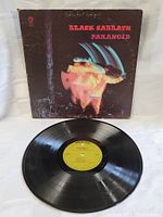 Front of the Black Sabbath Paranoid album cover with vinyl record displayed beneath it.