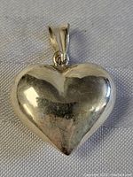 Close-up front view of large sterling silver heart pendant showing polished surface with light wear.