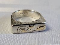 Front view of sterling silver ring with gold leaf design on flat top surface.