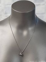 Photo showing the necklace worn on a display bust, highlighting the silver chain and black pendant.