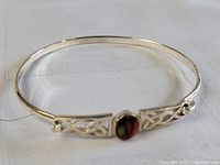 Front view of sterling silver bracelet with oval multi-color stone and open Celtic knot silverwork on sides.