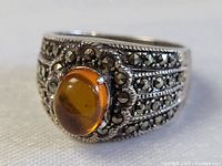 Close up front angled view of the sterling silver ring with amber centerpiece stone and marcasite accents.