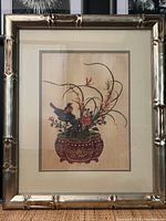 Full view of Chinese art print with flowers and a bird in a reddish planter, framed in silver bamboo style frame