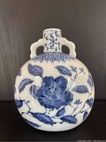 Front view of small round Fitz and Floyd ceramic vase with blue floral pattern on white.