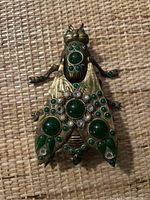 Top view of the brass fly-shaped ashtray showing green jeweled decoration and missing gems.