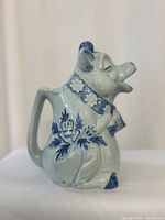 Side view of the vintage cow pitcher showing blue floral details and integrated handle.