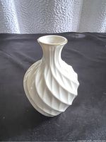 Side view of the white porcelain Lenox bud vase showing the swirl pattern and gold rim