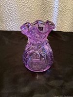 Front and side view of the hand blown amethyst glass vase showing the ruffled top and internal bubbles.