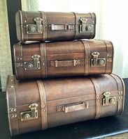 Stacked view of the three vintage wooden suitcases showing the leather handles and metal locking clasps.