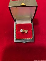 Pair of 14k gold stud earrings with clear zirconia stones on red velvet insert inside box, front view