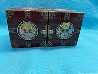 Front view of the jewelry box showing colorful circular inlays and metal corner accents.