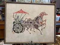 Framed artwork showing two horses pulling a chariot with two figures under a red canopy on rice paper.