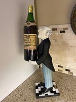 Full side view of statue holding large bottle-shaped tray on a countertop.