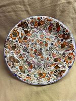 Full view of the large round porcelain plate showcasing colorful floral hand-painted design and gold leaf accents.