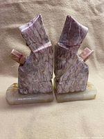 Front view of two pink marble monk figurine bookends on matching bases.