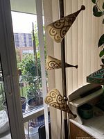 Full view of chrome metal pole lamp showing three beige shades with brown scroll pattern