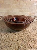 Four purple glass nesting bowls stacked inside each other, showing largest bowl on bottom.
