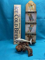 All three items arranged together showing the beer sign, wall organizer, and dolphin figurine on wood base.