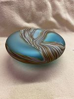 Side angle showing the rounded blue opalescent glass bowl with brown and white swirled abstract design