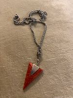 Full view of the silver chain and the triangular red coral pendant showing texture and color of coral and the pendant attachment.