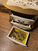 Jewelry box with drawers open showing assorted costume jewelry pieces inside