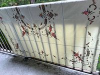 Full view of the vintage style tablecloth spread out showing embroidered floral and cutwork detailing.