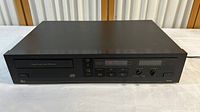 Front view of the Dbx DX 3 CD player showing the tray slot, display, and control buttons.