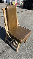 Front view of the chair showing driftwood rattan frame and olive vinyl cushions, highlighting condition and texture.