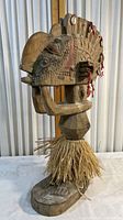 Front side view of the hand carved wooden tribal artwork statuette showing detailed face, arms, skirt, and base.