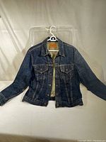 Front view of jacket on hanger showing pockets, buttons, stitching and overall condition
