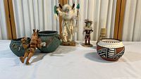 Full view of collection showing pottery pieces and kachina dolls arranged on white cloth background