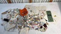 Wide view of loose used stamps, vintage album pages, envelopes, and a green folder on a table.