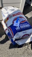 Photo of three large bags stacked outside on the ground, Kingsford charcoal The Original 20 lb bags.